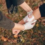 providing-first-aid-park-man-bandaged-injured-arm-guy-helps-friend